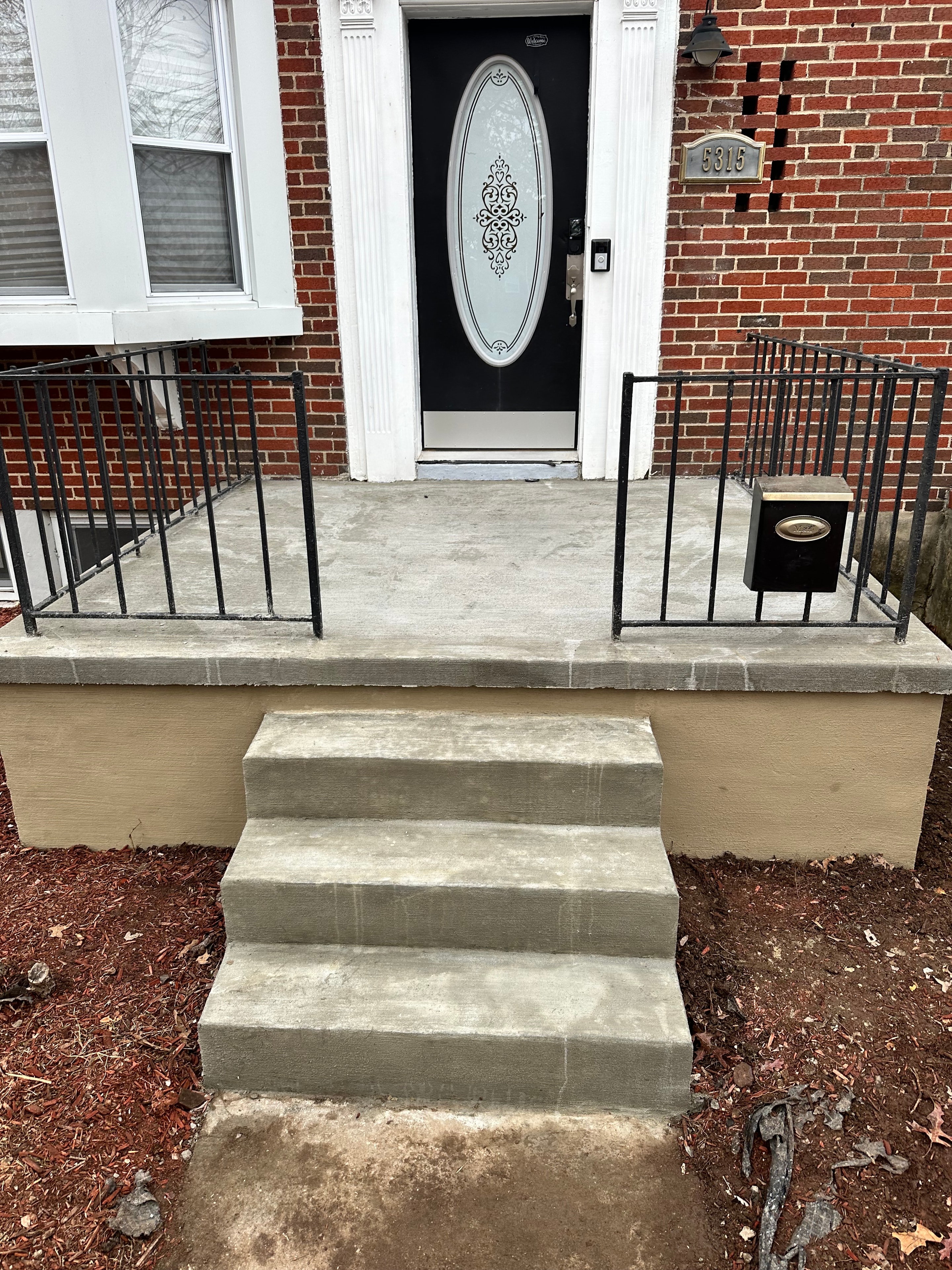 Concrete entry steps and landing at a brick home