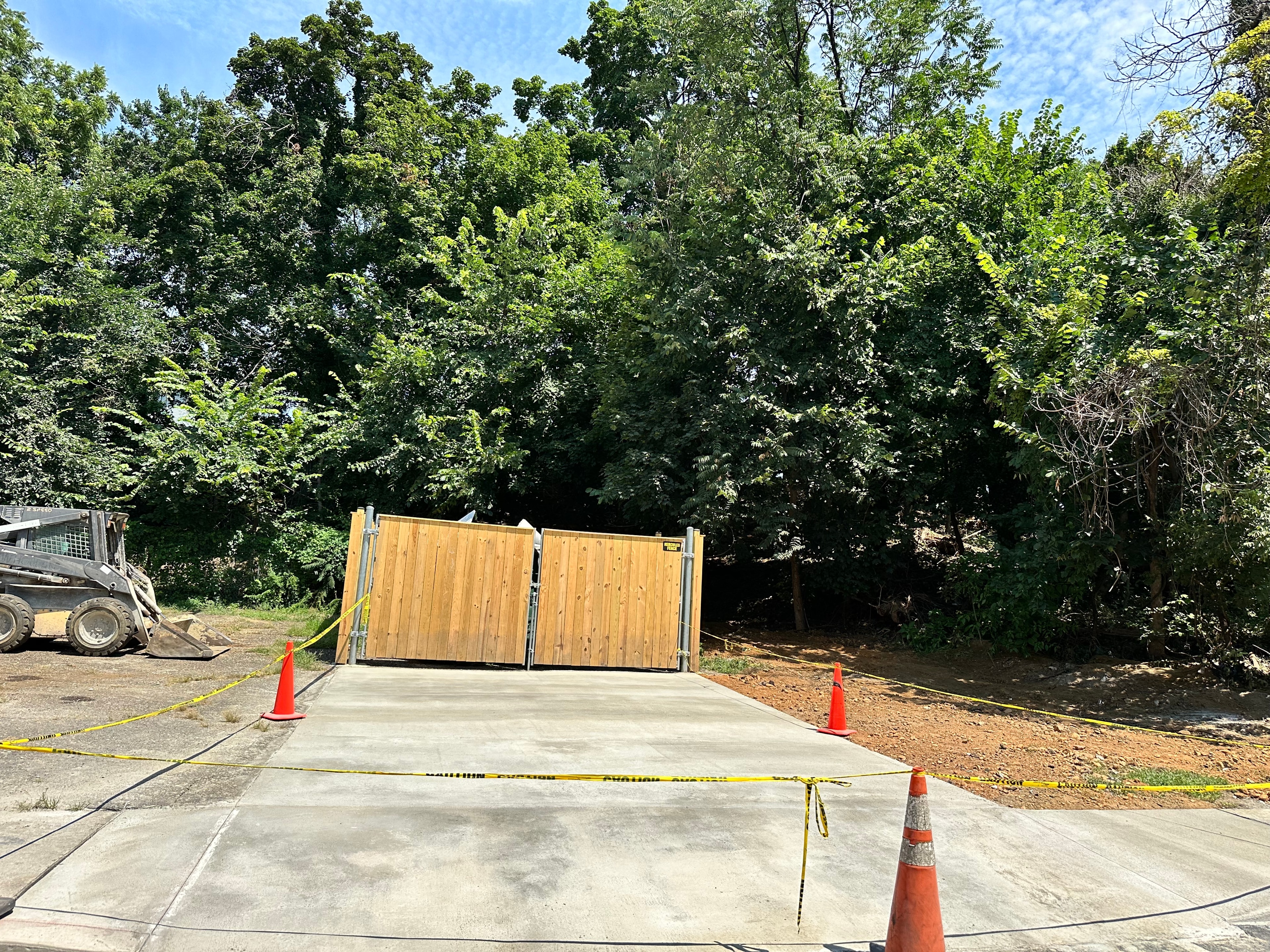 New concrete driveway pad with gates and safety cones