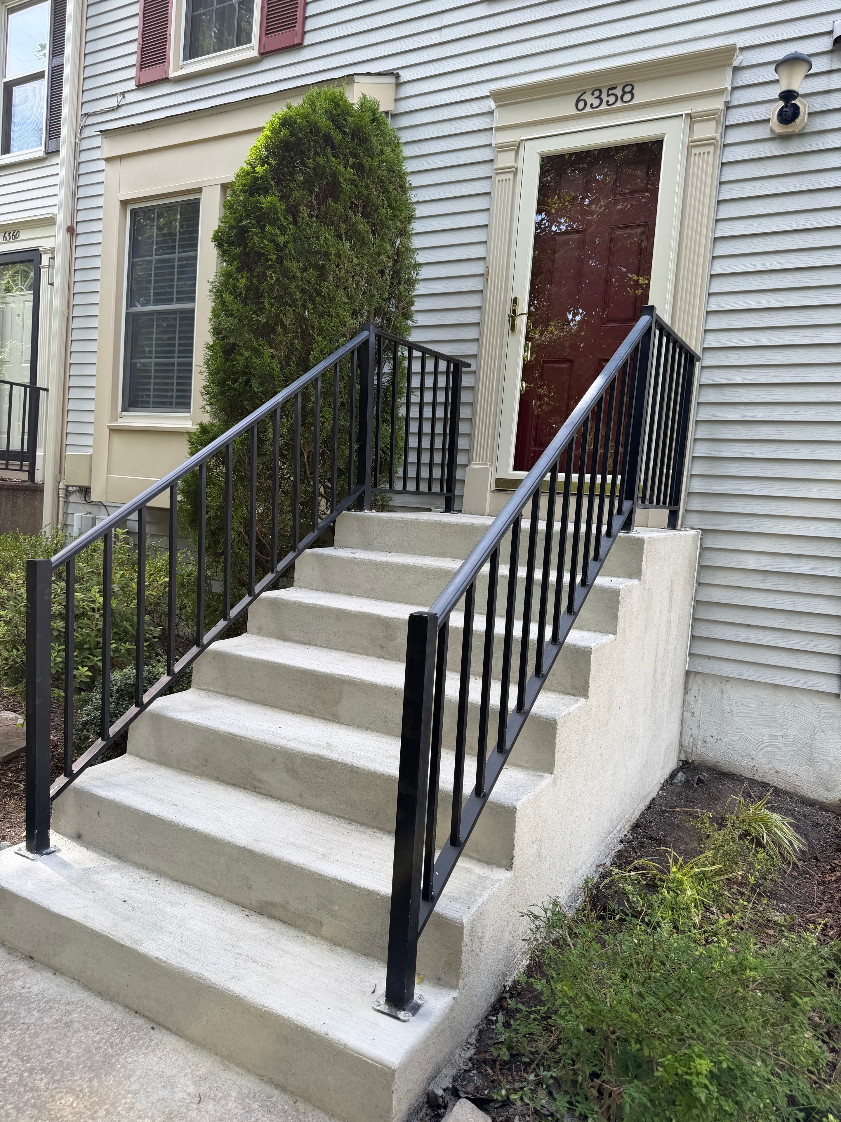 Finished concrete steps with black railings at a residential entrance
