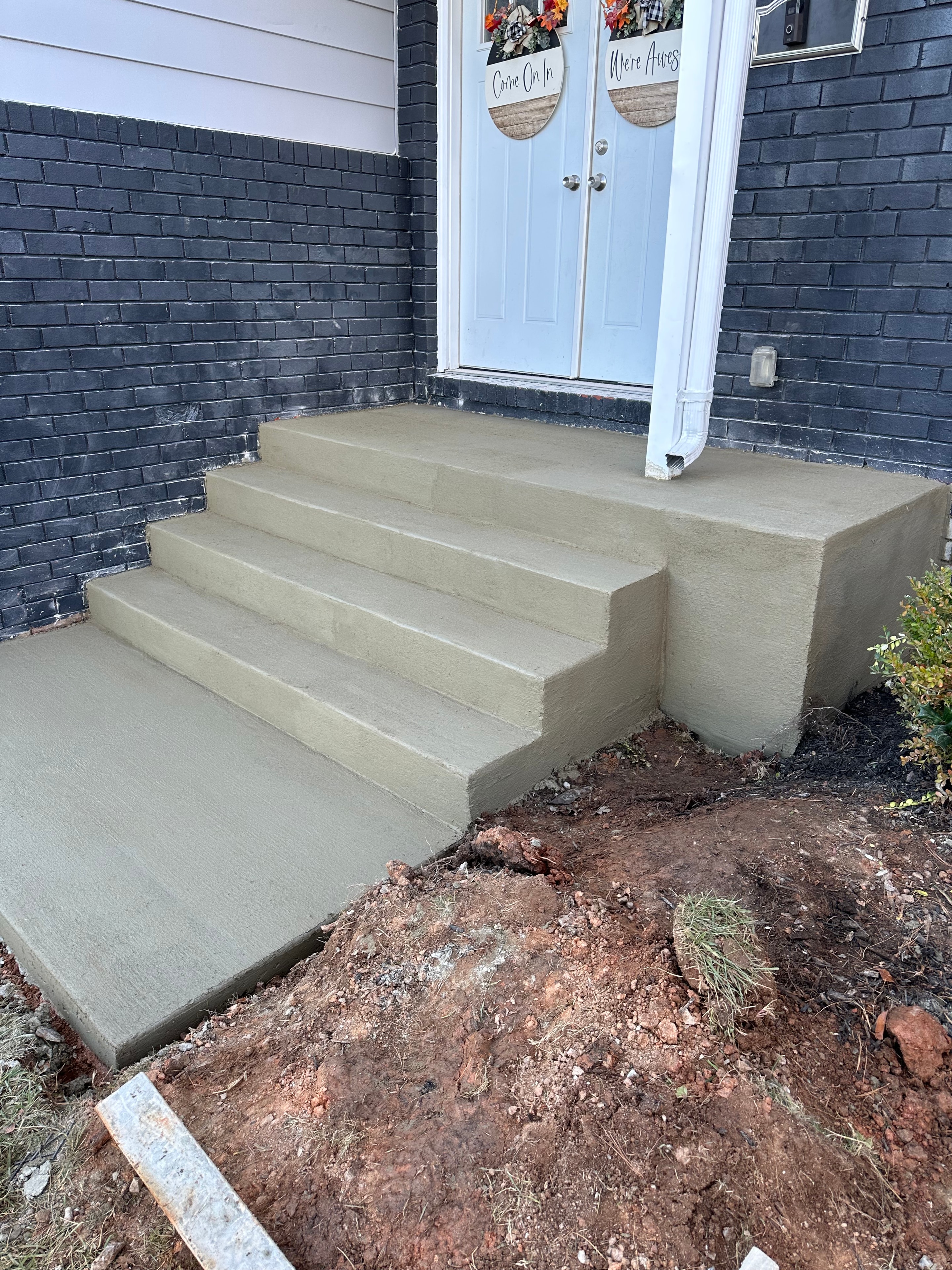 Fresh concrete entry steps at a dark brick home