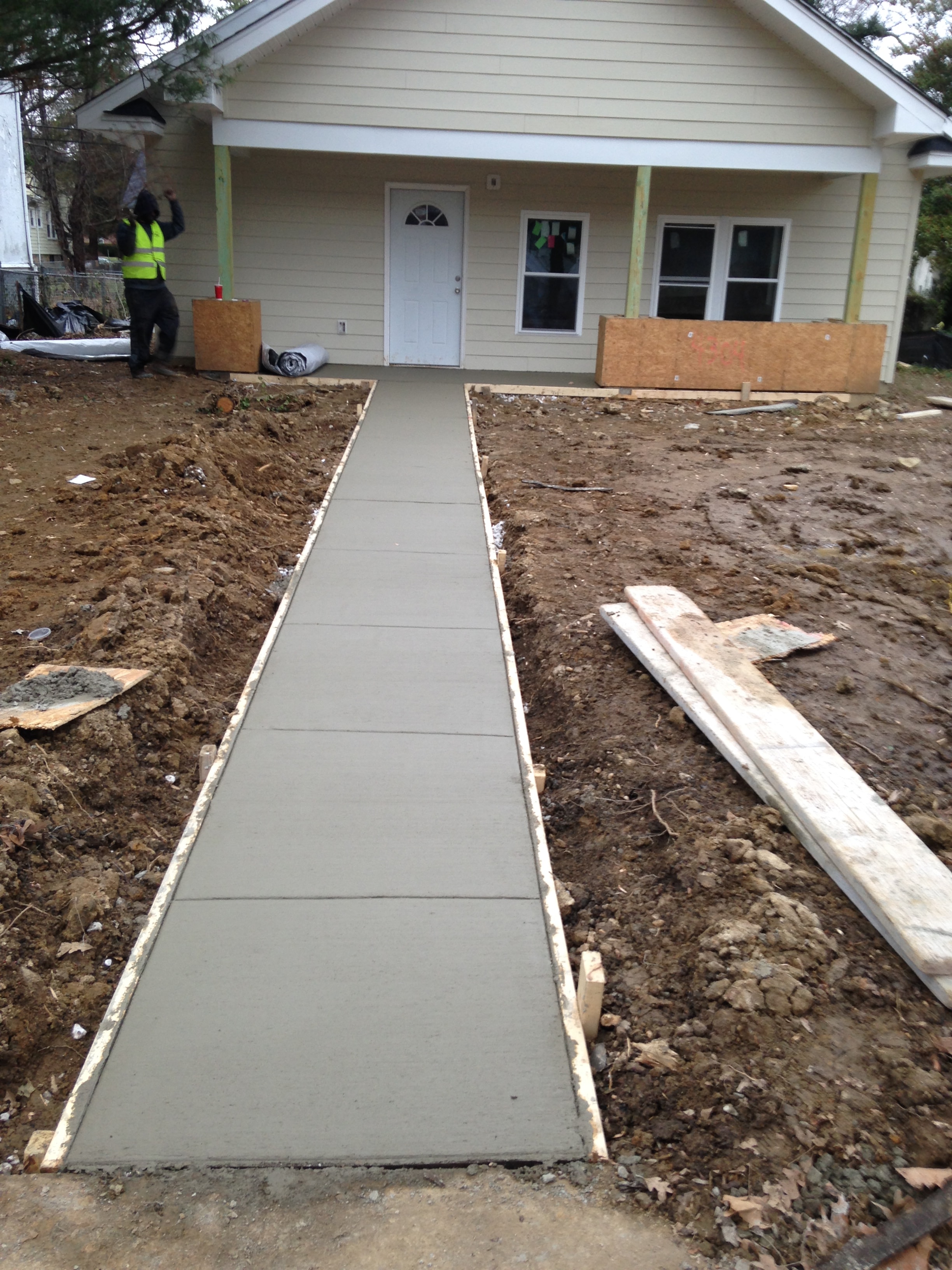 Freshly poured concrete walkway leading to a residential entrance