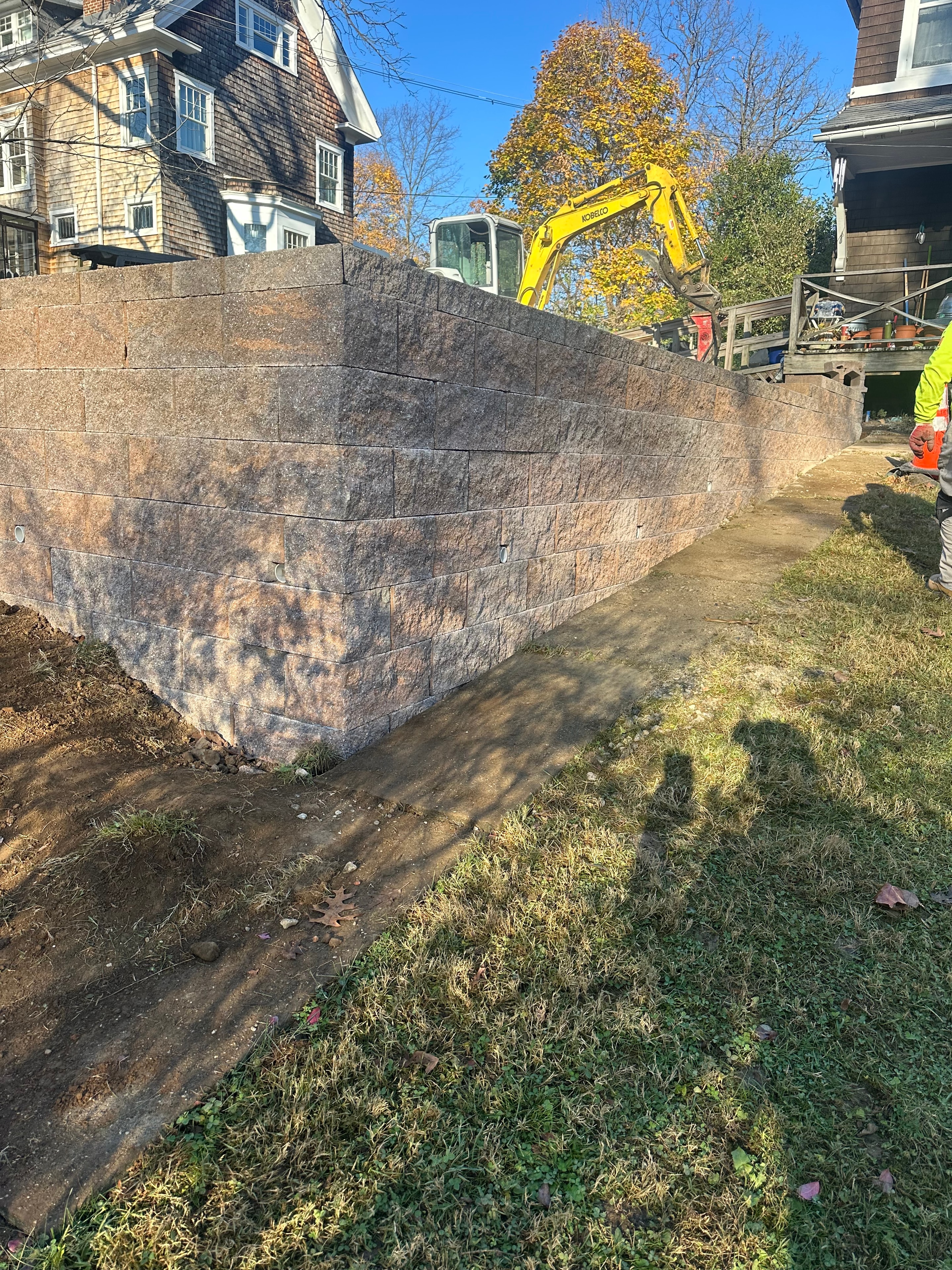 Stone retaining wall installation with excavation equipment