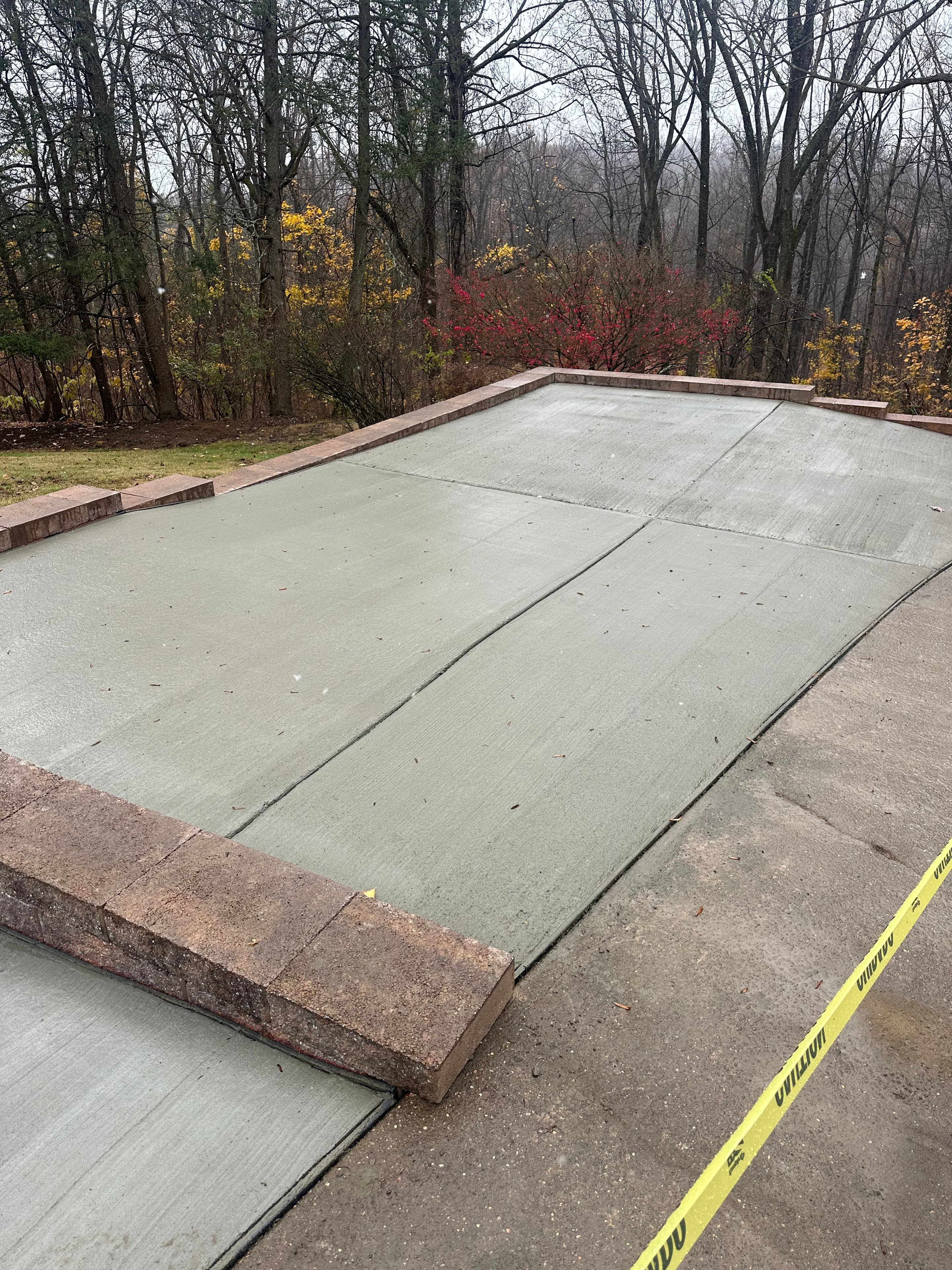 New concrete walkway bordered by landscaping in a wooded setting